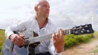 人在大自然中弹吉他，在田野里唱歌.. 吉他手触摸吉他弦。 中弹。